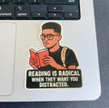 A sticker with an illustration of a person reading a book, accompanied by the text "Reading is Radical When They Want You Distracted."