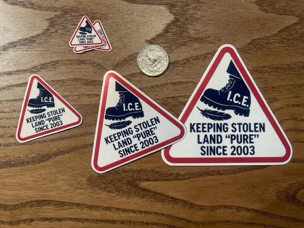 Five triangular abolish ice sticker designs in different sizes laid on a wood table next to a quarter for scale, each showing the I.C.E. boot stomping a feather.