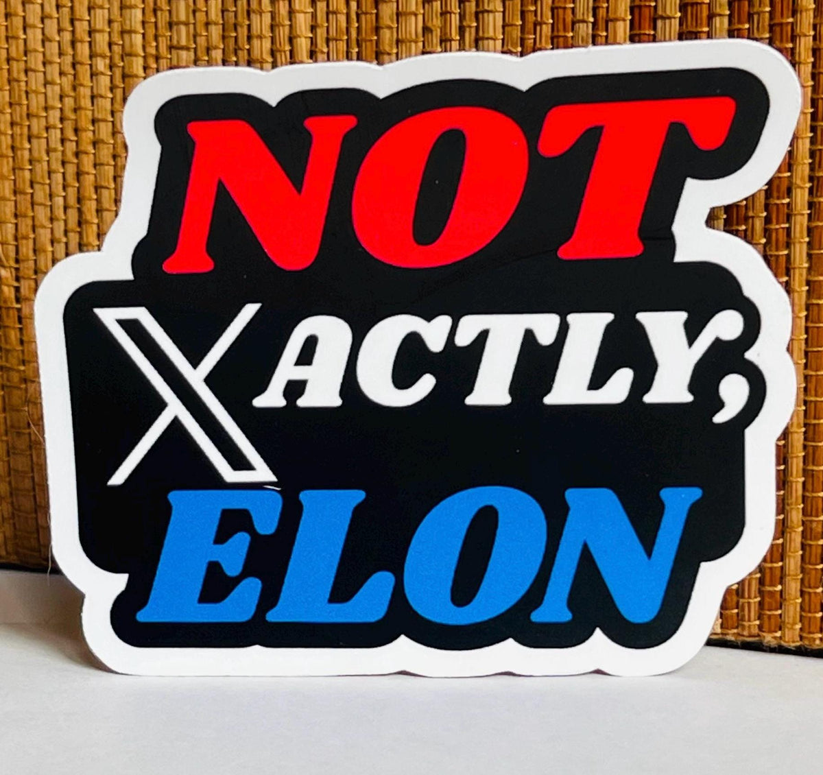 A sticker with the text "NOT ACTLY, ELON" in bold, red and blue letters.