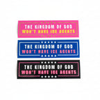 A person is holding a BUMPER sticker with the text "The Kingdom of God Won't Have Ice Agents" on it.