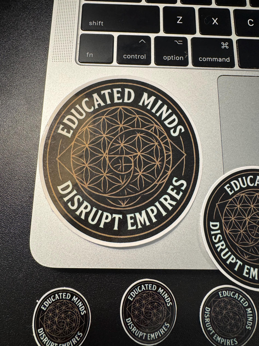 a laptop with several stickers on it, including one that says "EDUCATED MINDS DISRUPT EMPIRES".