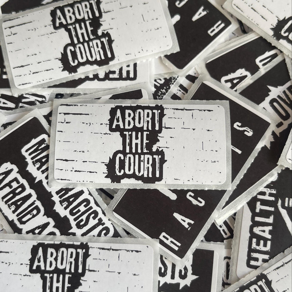 a collection of black and white stickers with the text "Abort the Court" printed on them.