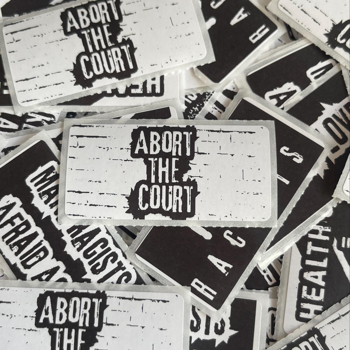a collection of black and white stickers with the text "Abort the Court" printed on them.