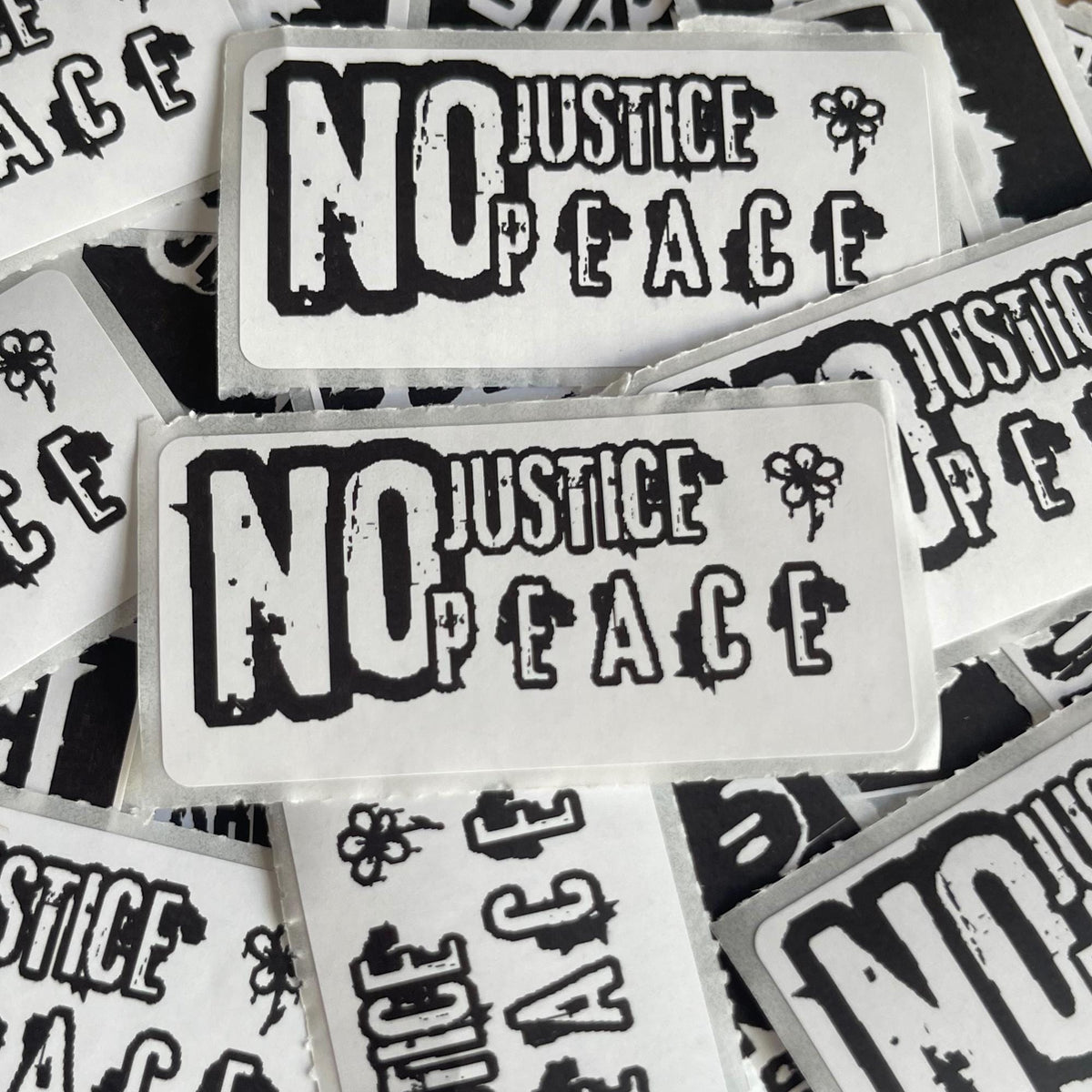 multiple stickers with the text "NO JUSTICE / PEACE" printed on them.