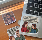 A collection of funny meme stickers spread across a wooden desk and laptop corner, including a grumpy grandmother knitting an 'FDT' scarf with her cat, a comic panel joking about Jesus and Bernie Sanders, and the Jesus-said-love-your-neighbor sticker on the laptop lid.